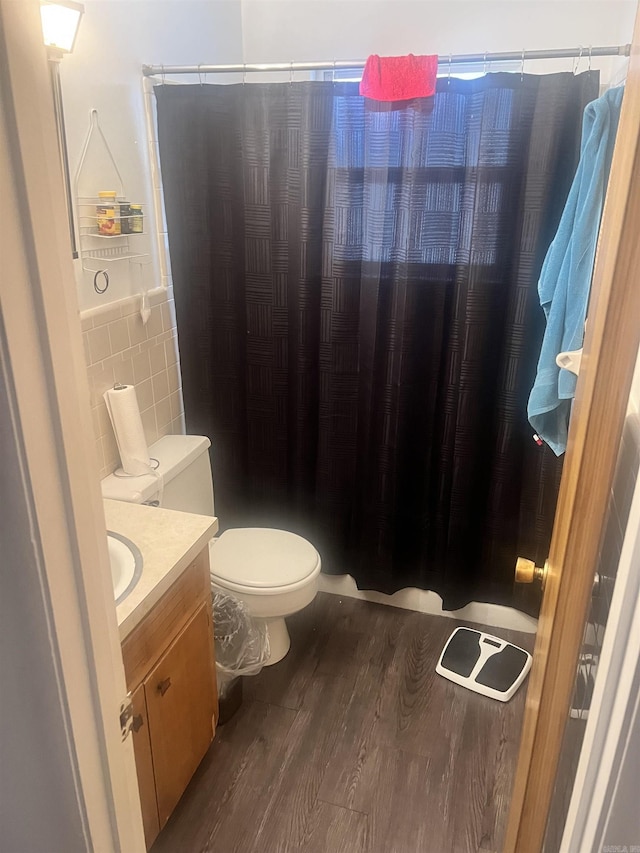 bathroom with wood-type flooring, toilet, tile walls, and vanity