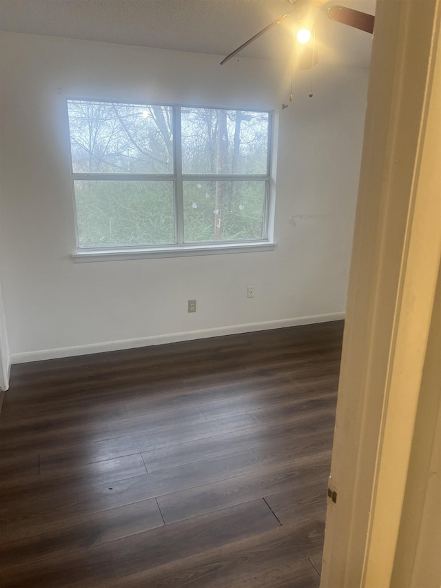 spare room with ceiling fan, dark wood-type flooring, and a healthy amount of sunlight