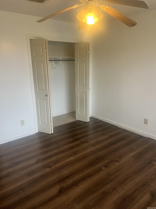 unfurnished bedroom with ceiling fan, dark hardwood / wood-style flooring, and a closet