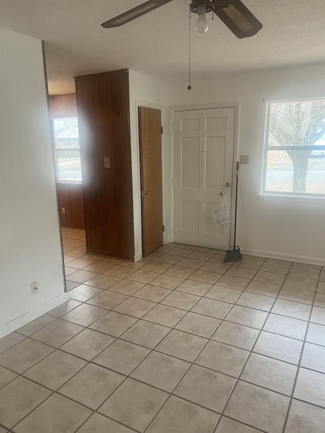 tiled spare room featuring a textured ceiling and ceiling fan