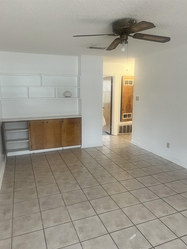 unfurnished room with ceiling fan, built in features, and a textured ceiling