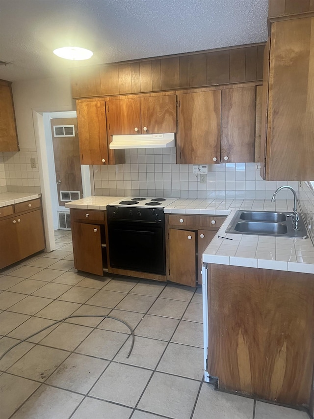 kitchen with light tile patterned flooring, sink, backsplash, electric range, and a textured ceiling