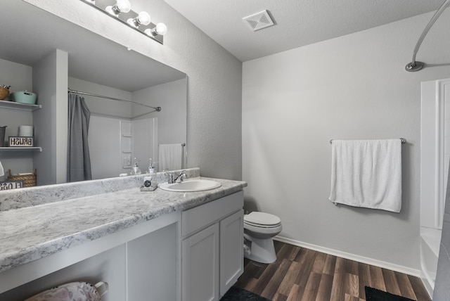 full bathroom featuring shower / tub combo with curtain, toilet, wood-type flooring, a textured ceiling, and vanity