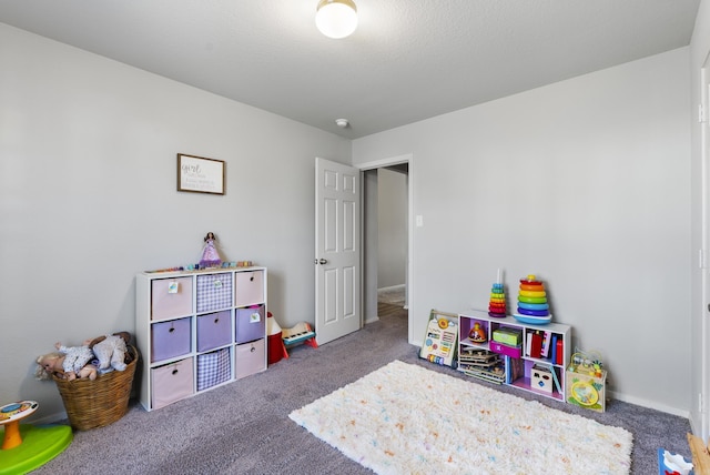 recreation room featuring dark carpet and a textured ceiling