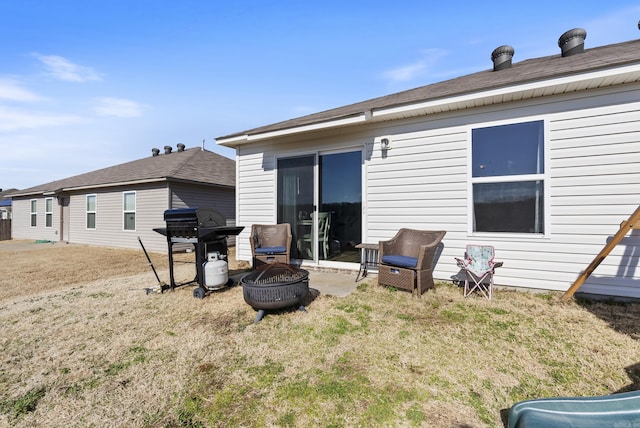 back of property with a lawn and an outdoor fire pit