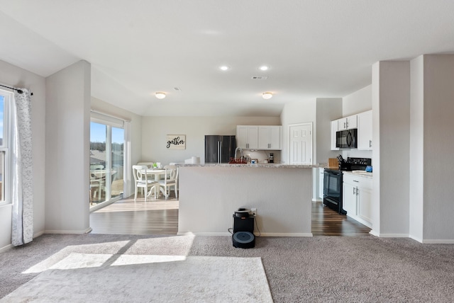 kitchen with dark colored carpet, a center island with sink, white cabinets, and black appliances