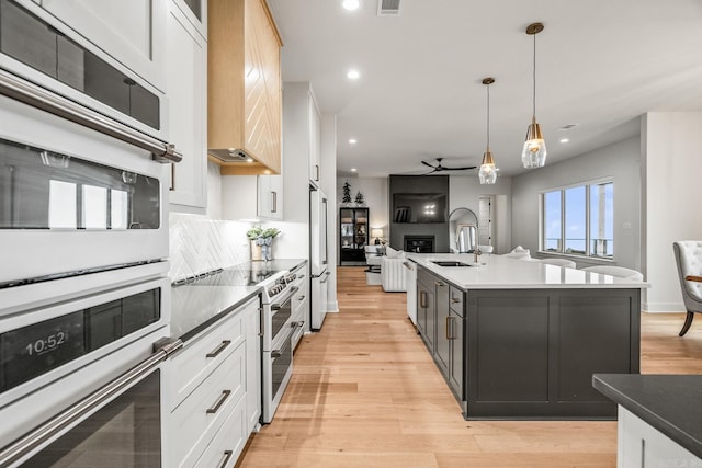 kitchen featuring white cabinetry, decorative light fixtures, and an island with sink