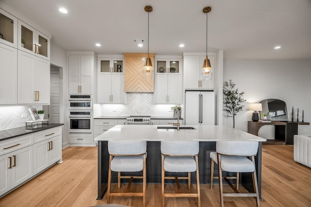 kitchen featuring white cabinetry, double oven, decorative light fixtures, and high end refrigerator