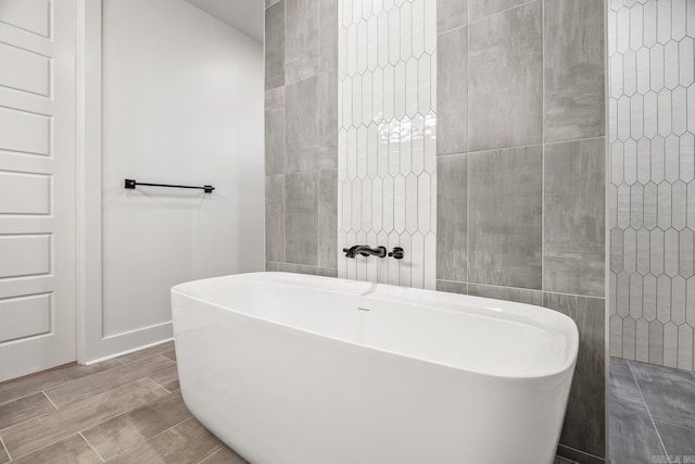 bathroom with a washtub and tile walls