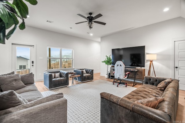 living room with ceiling fan, lofted ceiling, and light hardwood / wood-style floors