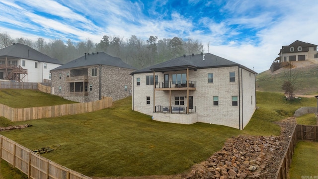 back of property with a yard and a balcony