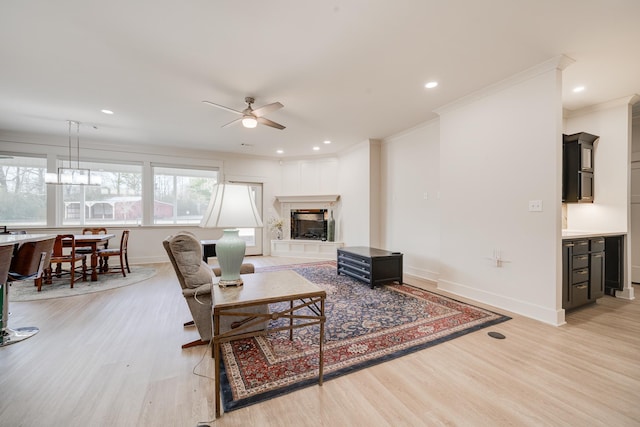 living room with crown molding, ceiling fan, and light hardwood / wood-style floors