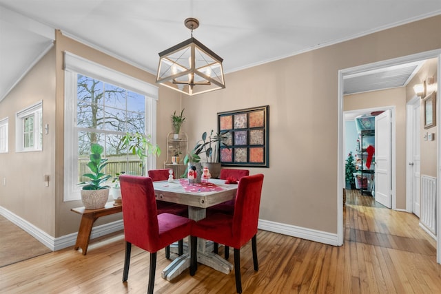 dining space featuring baseboards, ornamental molding, light wood-type flooring, and an inviting chandelier