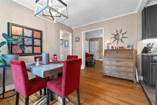 dining space featuring crown molding, light hardwood / wood-style flooring, and a notable chandelier