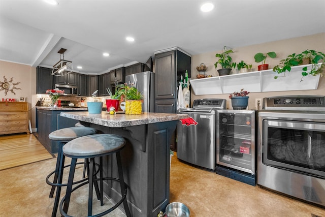 kitchen featuring dark brown cabinetry, wine cooler, a kitchen island, appliances with stainless steel finishes, and light countertops