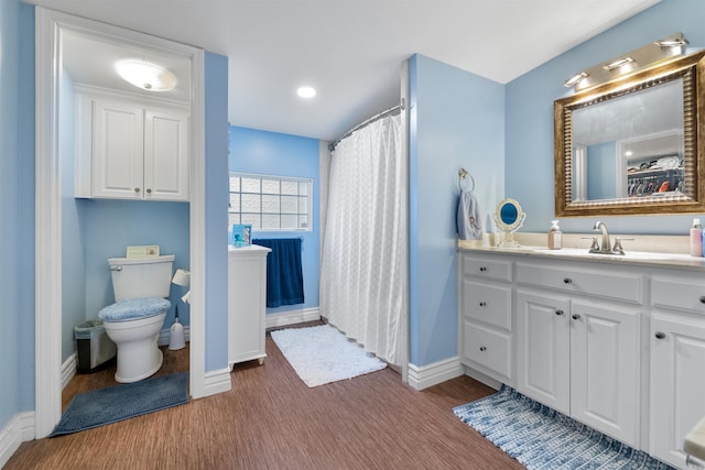 bathroom with a shower with shower curtain, toilet, vanity, wood finished floors, and baseboards