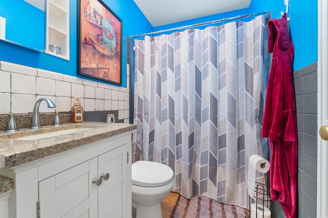 bathroom featuring tile walls, hardwood / wood-style floors, vanity, curtained shower, and toilet