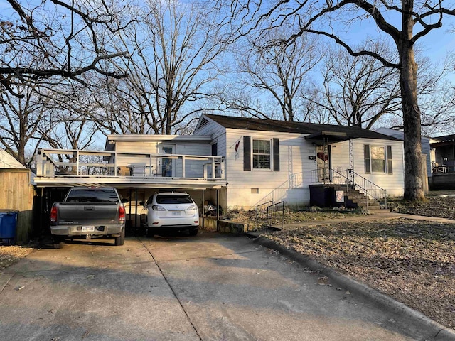 view of front of home with a balcony, a carport, and central air condition unit