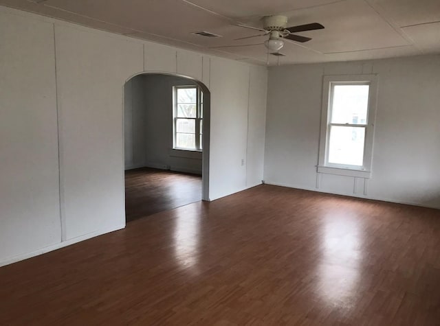 unfurnished room featuring ceiling fan, a healthy amount of sunlight, and dark hardwood / wood-style floors