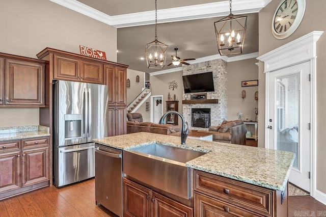 kitchen featuring pendant lighting, a fireplace, sink, a kitchen island with sink, and stainless steel appliances