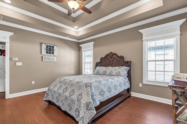 bedroom featuring crown molding, dark wood-type flooring, ceiling fan, and a tray ceiling