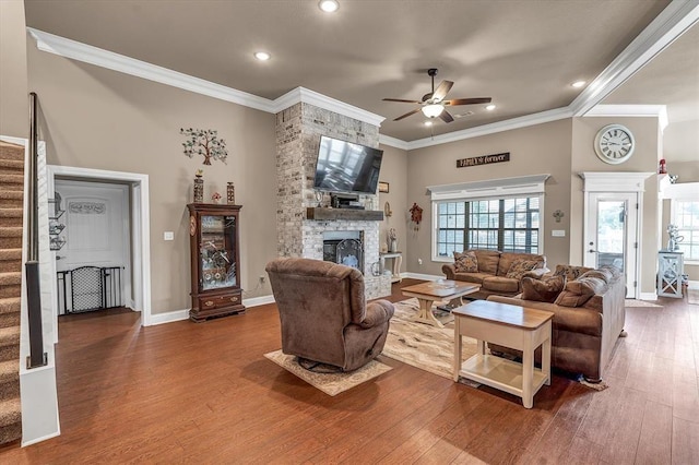 living room with crown molding, a stone fireplace, ceiling fan, and hardwood / wood-style flooring