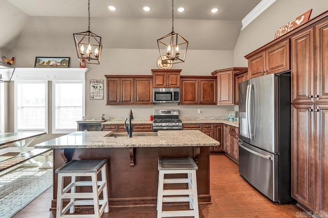 kitchen with appliances with stainless steel finishes, a kitchen island with sink, sink, and a kitchen breakfast bar