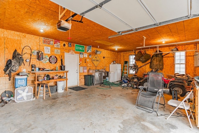 garage featuring white refrigerator, a garage door opener, and wooden walls