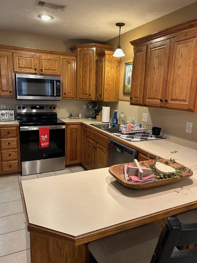 kitchen featuring stainless steel appliances, a kitchen bar, kitchen peninsula, and decorative light fixtures