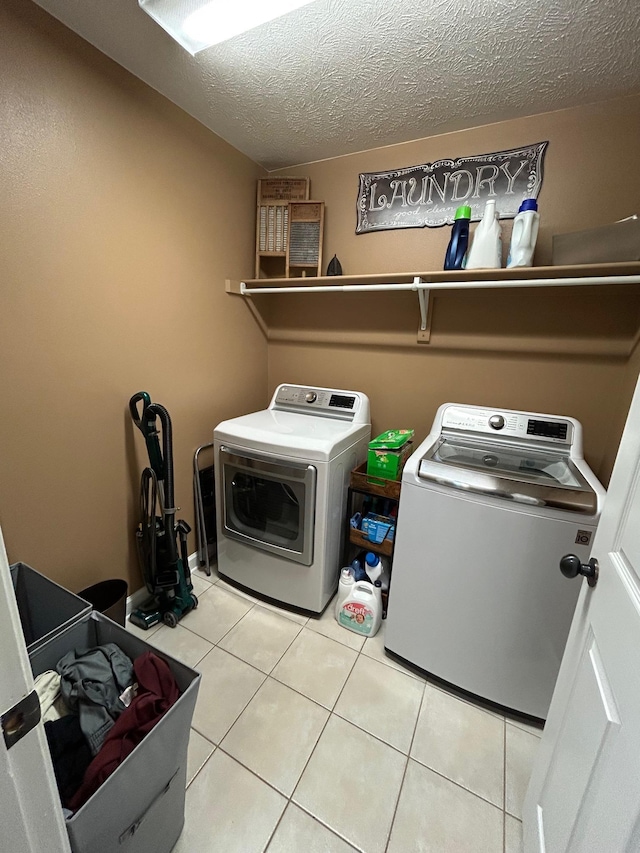 washroom with light tile patterned floors, washer and clothes dryer, and a textured ceiling