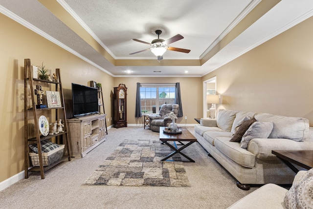 living room featuring a tray ceiling, carpet floors, ornamental molding, and ceiling fan