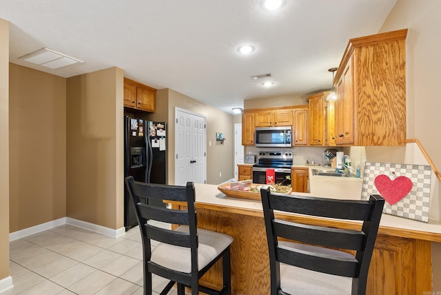 kitchen with a kitchen bar, sink, light tile patterned floors, appliances with stainless steel finishes, and kitchen peninsula