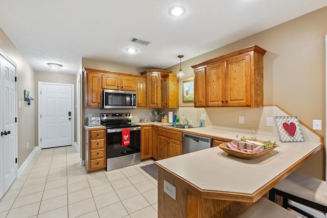 kitchen featuring hanging light fixtures, a breakfast bar, kitchen peninsula, and appliances with stainless steel finishes