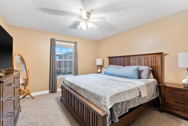 bedroom with ceiling fan, light colored carpet, and a textured ceiling