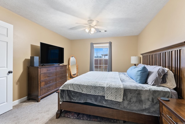 bedroom featuring ceiling fan, light carpet, and a textured ceiling