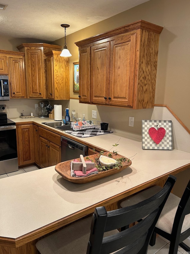 kitchen featuring a breakfast bar, hanging light fixtures, light tile patterned floors, kitchen peninsula, and stainless steel appliances