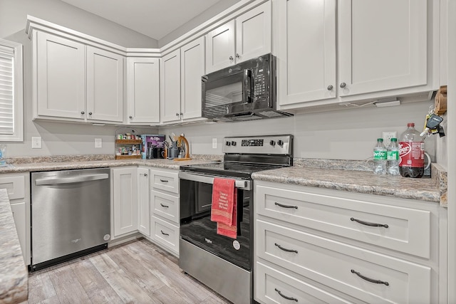 kitchen featuring stainless steel appliances, light stone counters, white cabinets, and light hardwood / wood-style floors