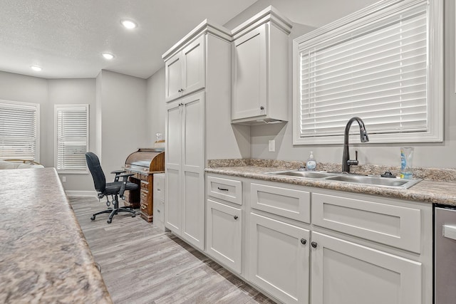 kitchen with sink, light hardwood / wood-style flooring, dishwasher, a textured ceiling, and white cabinets