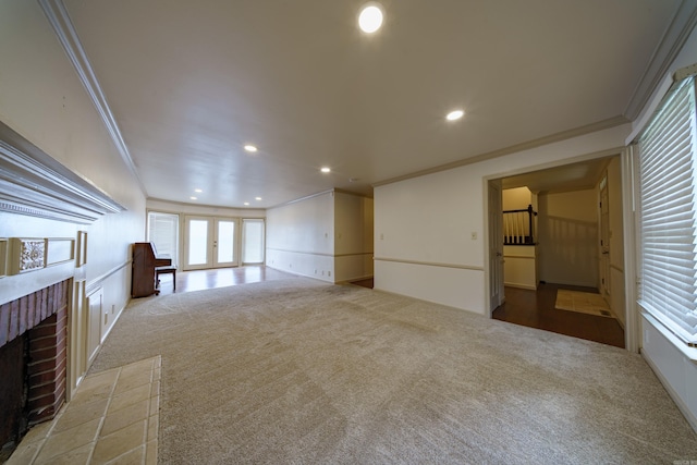 unfurnished living room with crown molding, a fireplace, french doors, and carpet flooring