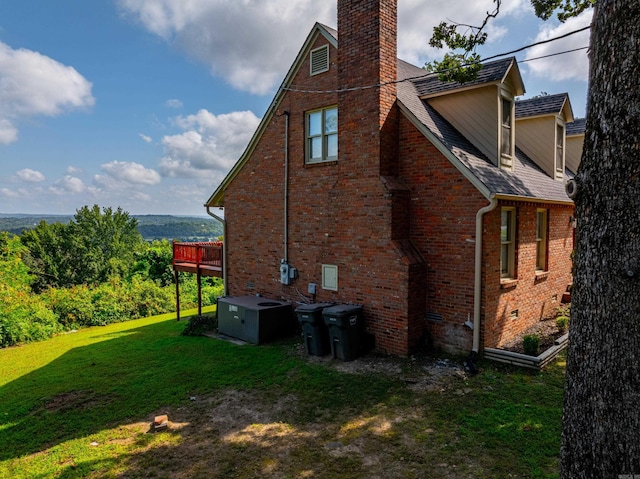 view of side of property featuring central AC unit, a yard, and a deck