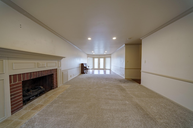 unfurnished living room featuring crown molding, a fireplace, light colored carpet, and french doors