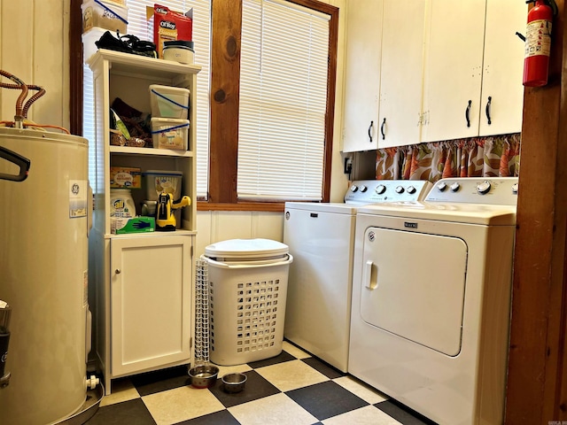 laundry room featuring water heater, washer and clothes dryer, and cabinets