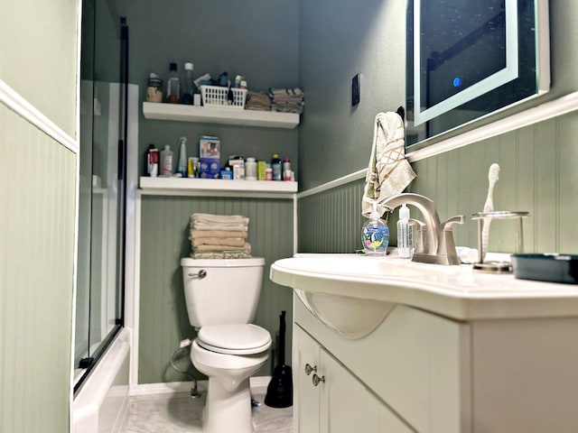 full bathroom with vanity, bath / shower combo with glass door, and toilet