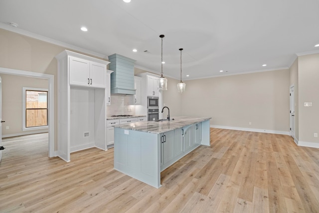 kitchen with decorative light fixtures, white cabinets, light stone counters, stainless steel appliances, and a spacious island