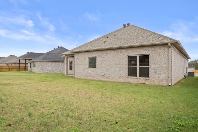 rear view of property with a yard and central AC unit