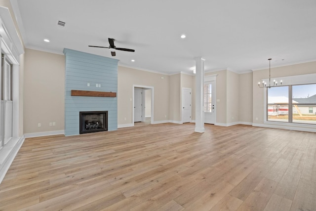 unfurnished living room with ceiling fan with notable chandelier, ornamental molding, a large fireplace, and light wood-type flooring