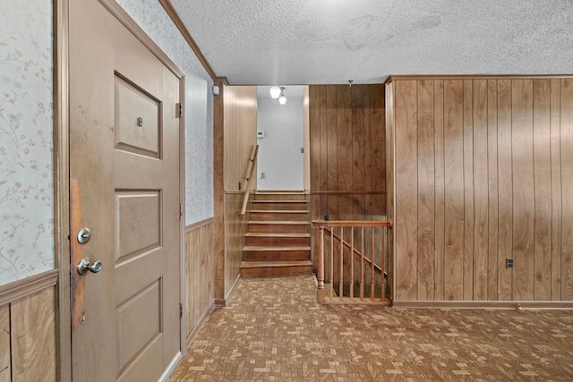 interior space with parquet flooring, a textured ceiling, and wood walls