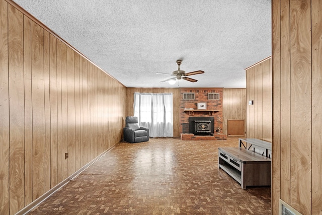 unfurnished living room with wooden walls, parquet floors, a textured ceiling, and ceiling fan