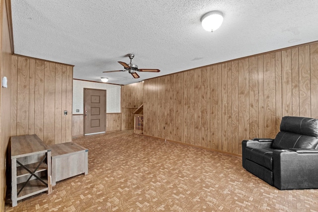 unfurnished room featuring ceiling fan, light parquet flooring, wooden walls, and a textured ceiling