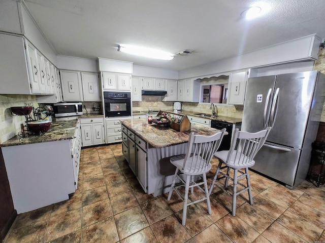 kitchen featuring white cabinetry, a center island, a kitchen bar, and black appliances